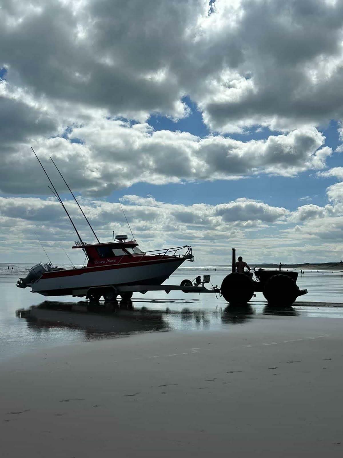 Boat being retrieved by beach tractor on a New Zealand beach